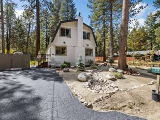Charming A-frame home nestled among tall pine trees, offering a serene mountain retreat.