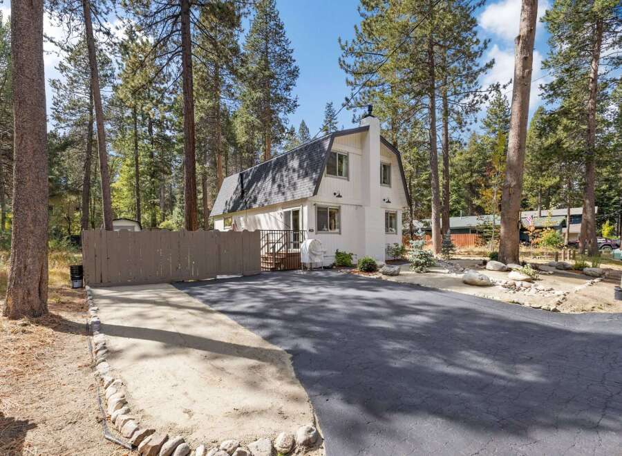 Nestled amidst tall pine trees, this charming white home offers a serene mountain retreat.