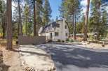 Nestled amidst tall pine trees, this charming white home offers a serene mountain retreat.