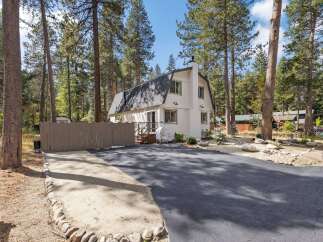 Nestled amidst tall pine trees, this charming white home offers a serene mountain retreat.