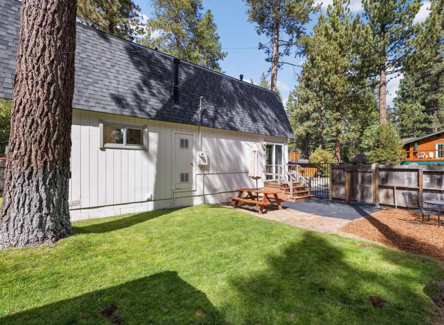 Enjoy outdoor living in this charming backyard featuring a picnic table and umbrella, perfect for al fresco dining.