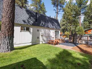 Enjoy outdoor living in this charming backyard featuring a picnic table and umbrella, perfect for al fresco dining.
