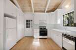 This charming kitchen features white cabinetry with gold hardware, a gas range, and a built-in microwave.