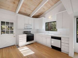 Charming kitchen featuring white cabinetry, a gas range, and a dishwasher, perfect for home chefs.