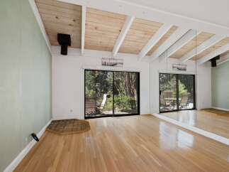 Experience the charm of this spacious living area, featuring a vaulted wood-paneled ceiling with exposed beams that add architectural interest.