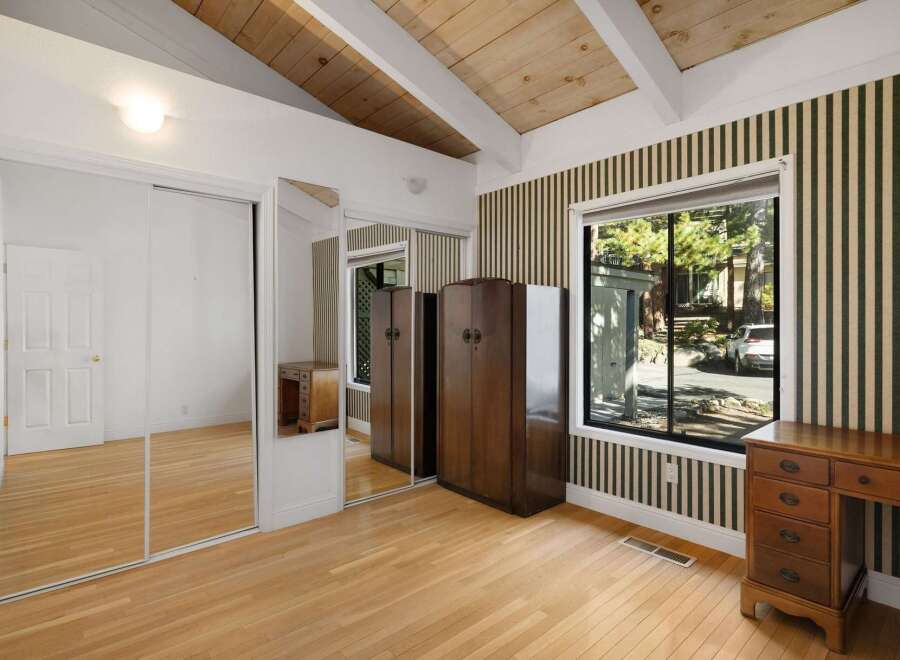 This charming bedroom features a vaulted wood-beamed ceiling and a large window offering scenic views.