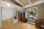 This charming bedroom features a vaulted wood-beamed ceiling and a large window offering scenic views.