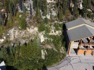 Experience mountain living in this stunning property nestled amongst lush evergreen trees and rocky terrain.