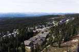Discover this stunning mountain retreat nestled amidst a dense evergreen forest, offering breathtaking panoramic views of rolling hills and distant blue mountains.