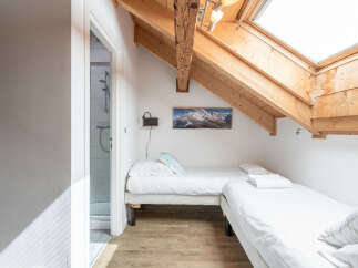 This charming attic bedroom features two twin beds, perfect for accommodating guests or family.