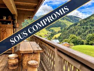 Experience the charm of mountain living with this stunning property, featuring a rustic wooden balcony overlooking breathtaking alpine scenery.