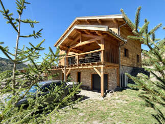 Experience mountain living in this stunning wooden chalet, featuring a stone base and a spacious balcony perfect for enjoying the alpine views.