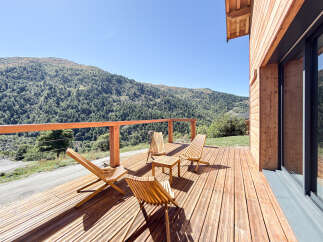Experience breathtaking mountain views from this stunning wooden deck, perfect for enjoying your morning coffee or evening relaxation.