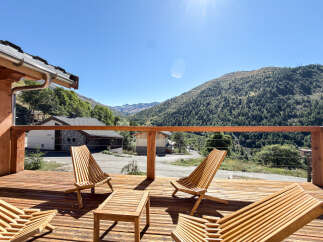 Enjoy breathtaking mountain views from this stunning wooden deck, complete with comfortable lounge chairs and a coffee table.