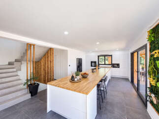 Discover this modern open-concept kitchen and living area, featuring a stunning wooden island perfect for entertaining.