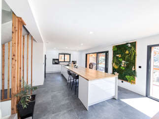 Experience modern living in this stunning open-plan kitchen and dining area, featuring a sleek white island with a natural wood countertop and bar stools.