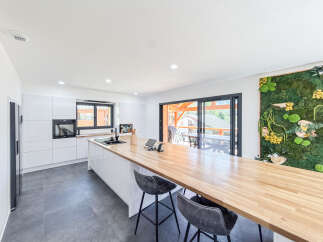 Experience modern living in this stunning kitchen featuring sleek white cabinetry and a spacious wooden island perfect for entertaining.