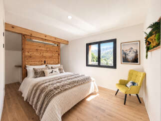 Experience rustic charm and modern comfort in this inviting bedroom, featuring a stunning wooden barn door and headboard that adds a unique, natural element.