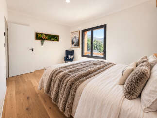 Experience breathtaking mountain views from this serene bedroom, featuring a cozy bed adorned with plush throws and decorative pillows.