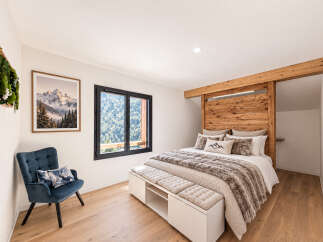Experience rustic charm in this cozy bedroom, featuring a stunning wooden headboard and a plush, fur-like throw blanket.