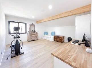 This spacious attic room features a dedicated home gym area with an elliptical machine, perfect for your fitness routine.