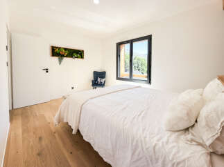 Experience modern comfort in this beautifully appointed bedroom, featuring a plush white duvet and a cozy accent chair.