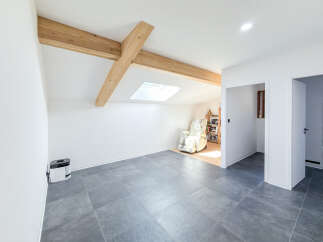 Discover this charming attic space featuring exposed wooden beams and a skylight that floods the room with natural light.