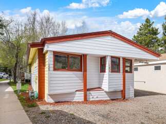 Charming single-family home featuring a bright white exterior with vibrant orange accents and a contrasting yellow side.