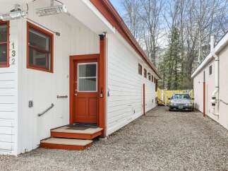 Discover this charming property featuring a bright white exterior with contrasting red trim, complemented by two outdoor heaters for year-round comfort.