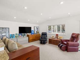 This spacious living area features a large flat-screen TV mounted above a wooden dresser, perfect for entertainment.