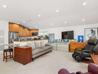 This spacious living area seamlessly integrates a modern kitchen with ample cabinetry and stainless steel appliances.