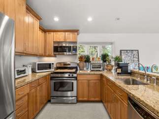 This spacious kitchen features beautiful light wood cabinetry complemented by granite countertops.