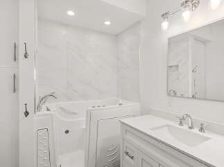 Experience ultimate relaxation in this beautifully appointed bathroom, featuring a luxurious walk-in tub with a sleek chrome faucet.