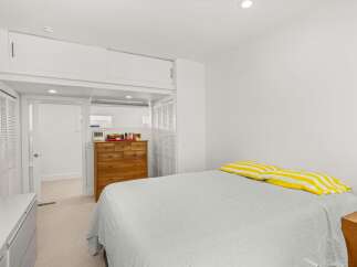 This bright and airy bedroom features a comfortable bed with cheerful yellow and white striped pillows, perfect for a restful night's sleep.
