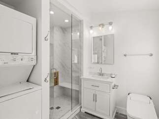 Experience modern convenience in this beautifully appointed bathroom, featuring a sleek glass-enclosed shower with marble tile and a built-in bench.