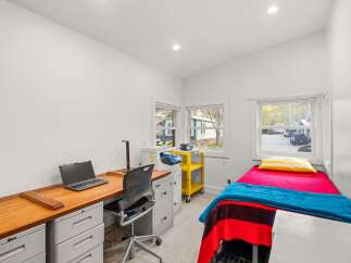 This versatile room features a functional workspace with a laptop and desk, perfect for remote work or study.