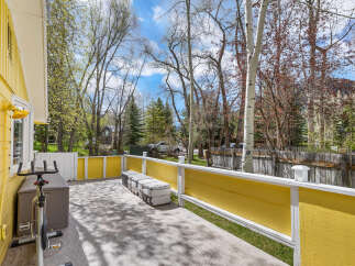 Enjoy the outdoors from this charming yellow-sided home featuring a spacious deck perfect for relaxation or entertaining.