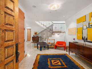 Step into a welcoming entryway featuring a grand wooden door and a striking abstract art piece.