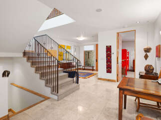 Step into this welcoming entryway featuring a grand staircase with ornate metal railings and plush carpeting.