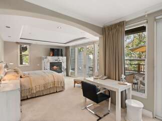 Experience luxury and comfort in this spacious bedroom featuring a cozy fireplace and a private balcony with stunning natural views.