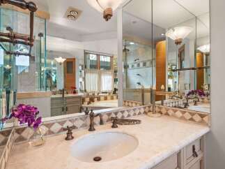 Experience luxury in this stunning bathroom featuring a spacious vanity with a marble countertop and elegant bronze fixtures.
