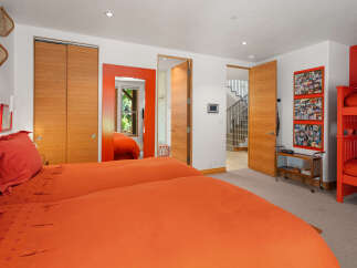 This vibrant bedroom features two twin beds with bright orange bedding, perfect for a lively and energetic atmosphere.