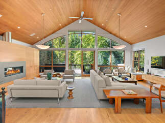 Experience luxurious living in this stunning modern home, featuring a soaring vaulted wood-paneled ceiling with a ceiling fan and recessed lighting.