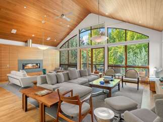 Experience luxurious living in this stunning great room, featuring a soaring vaulted ceiling with rich wood paneling and a modern gas fireplace.