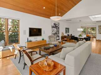 Experience luxurious living in this stunning open-concept living and dining area, featuring a warm wood-paneled ceiling and abundant natural light.