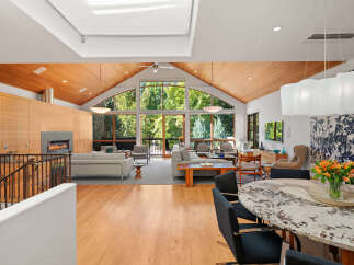 Experience luxurious living in this stunning home featuring a vaulted wood-paneled ceiling and expansive windows that flood the space with natural light.