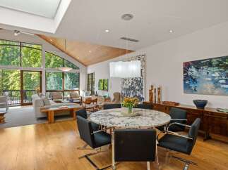 Experience luxurious living in this stunning open-concept space, featuring a vaulted ceiling with wood accents and expansive windows that flood the area with natural light.