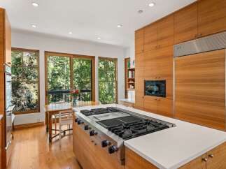 Experience luxury in this stunning kitchen featuring sleek, custom wood cabinetry and a professional-grade gas range on a spacious island.