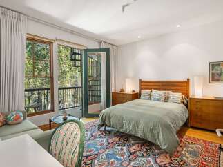 Experience serene living in this charming bedroom featuring a comfortable queen-sized bed with a stylish wooden headboard and a soothing sage green duvet.