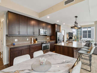 Experience modern living in this stunning condo featuring a gourmet kitchen with rich dark wood cabinetry, granite countertops, and a sleek mosaic tile backsplash.